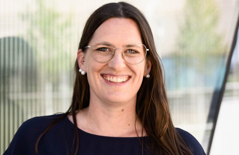 Kathrin Heimburger Lächelnde Frau mit lässiger Kleidung, Arme vor der Brust verschränkt.