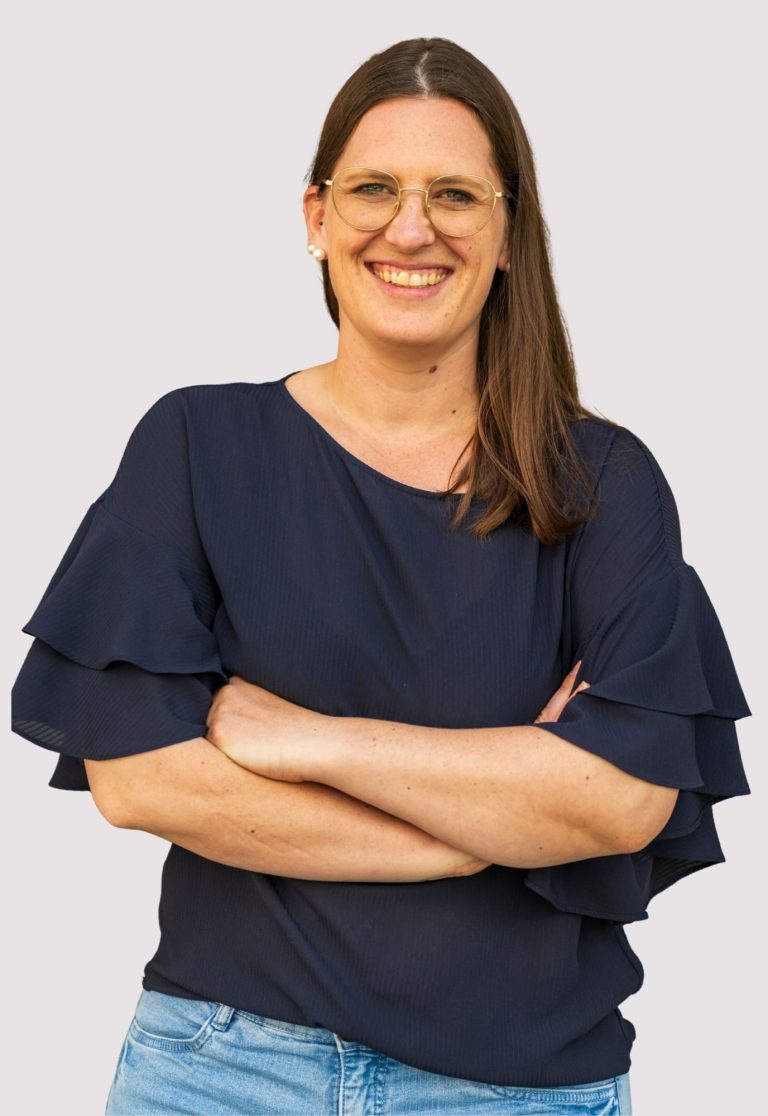 Kathrin Heimburger Lächelnde Frau mit lässiger Kleidung, Arme vor der Brust verschränkt.